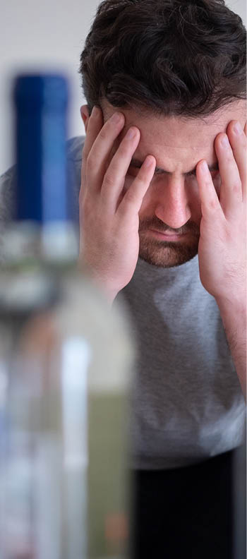 Alcohol addicted man portrait alone with spirit bottle